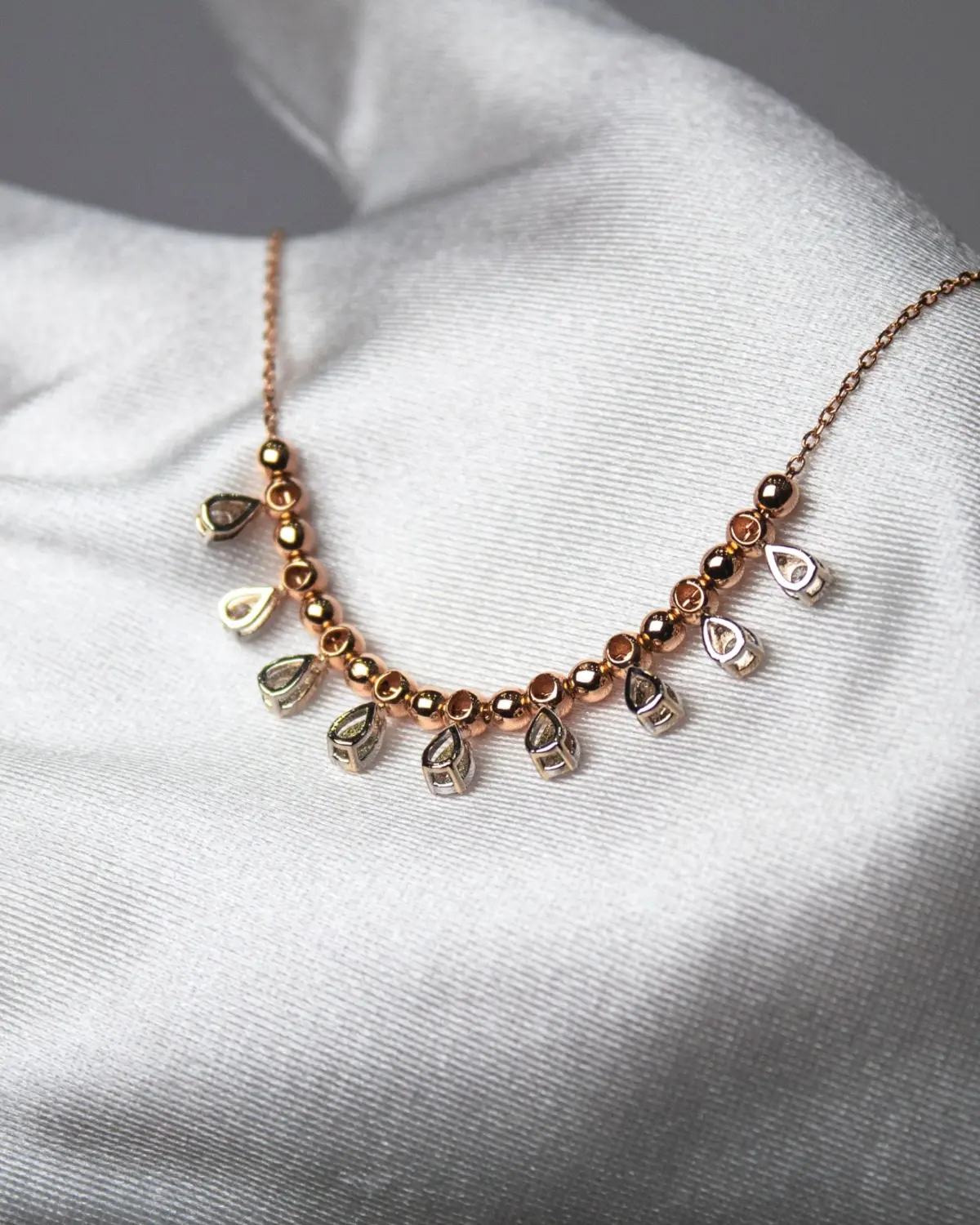Rose gold necklace arranged on satin fabric
